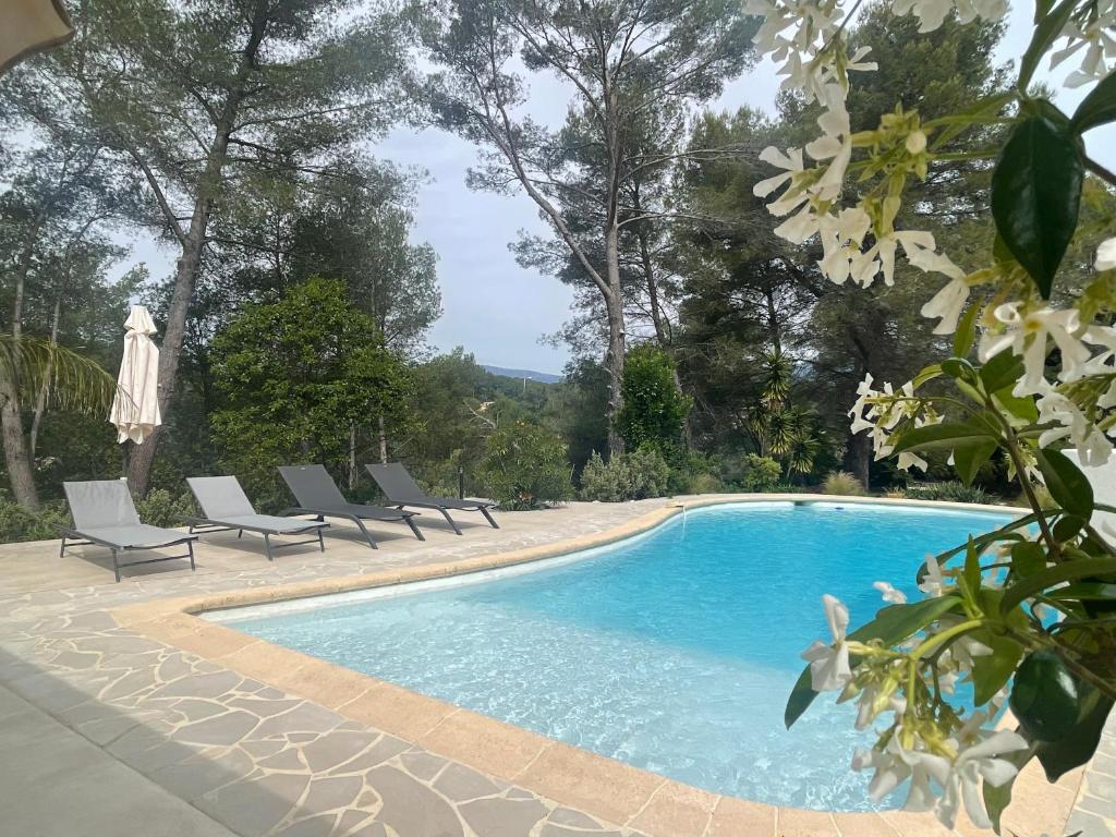 a swimming pool with lounge chairs and an umbrella at La villa des Carriers- maison avec piscine proche mer in Roquefort-les-Pins