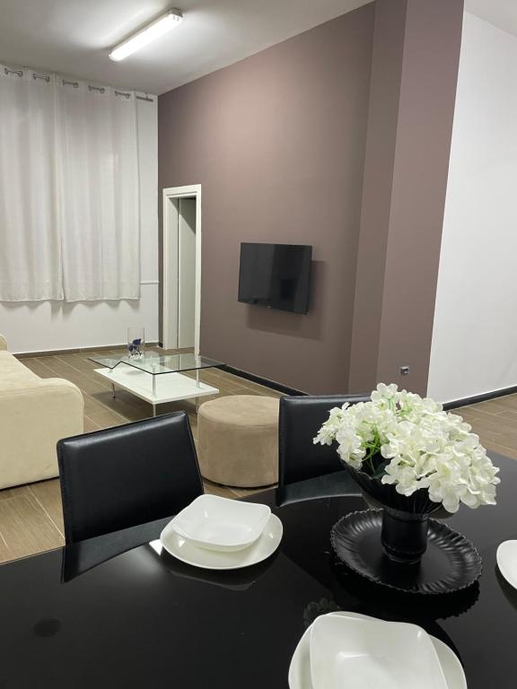 a living room with a black table with white flowers at Gold apartament vlore free parking in Vlorë