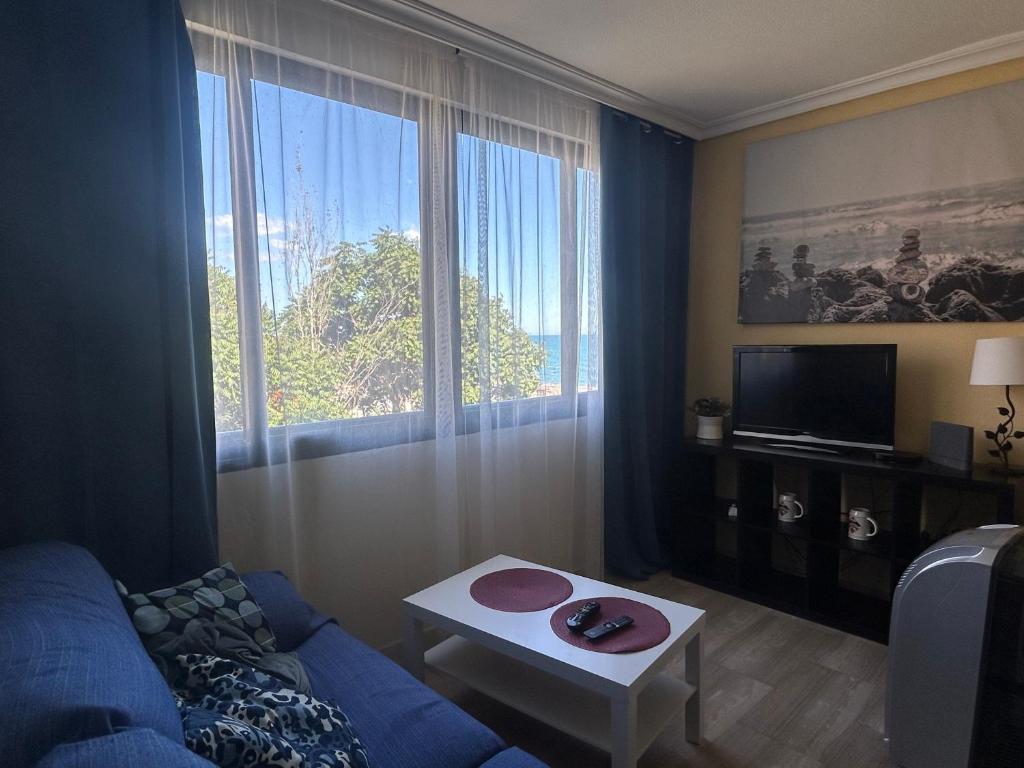 een woonkamer met een blauwe bank en een groot raam bij Apartment with Beach Views in Fuengirola