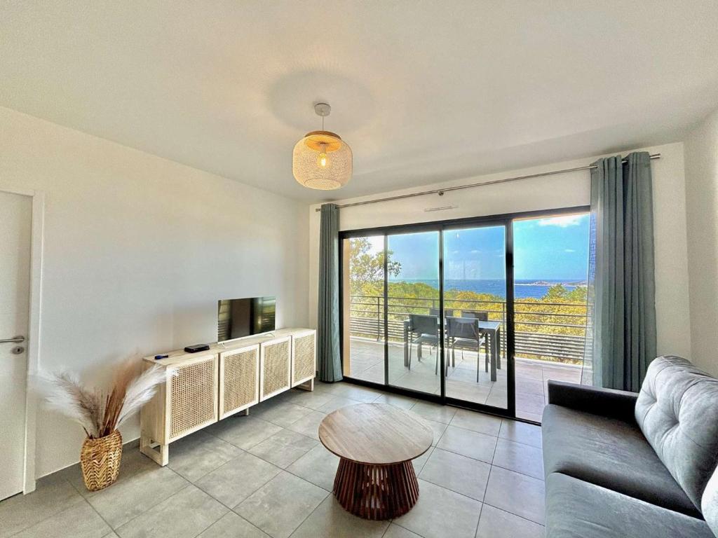 a living room with a couch and a table and a balcony at Appartement Tour d'Omigna Cargèse in Cargèse