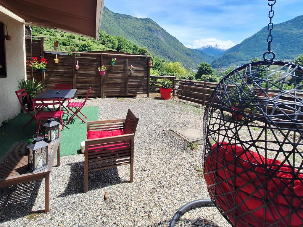 a patio with chairs and a table with mountains in the background at Appartement avec terrasse et parking Privé in Aigueblanche