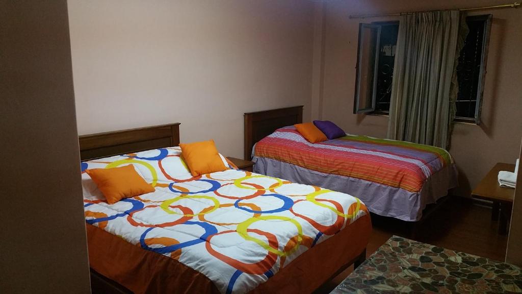 1 dormitorio con 2 camas y sábanas coloridas en Hostal Montufar, en Quito