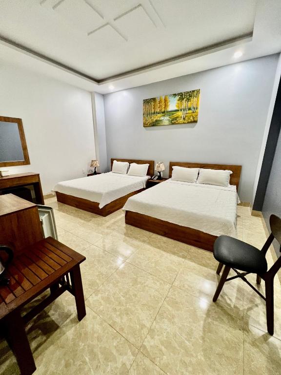 una habitación de hotel con 2 camas y una silla en Khách Sạn Trung Anh 78 HAI BÀ TRƯNG BMT, en Buon Ma Thuot