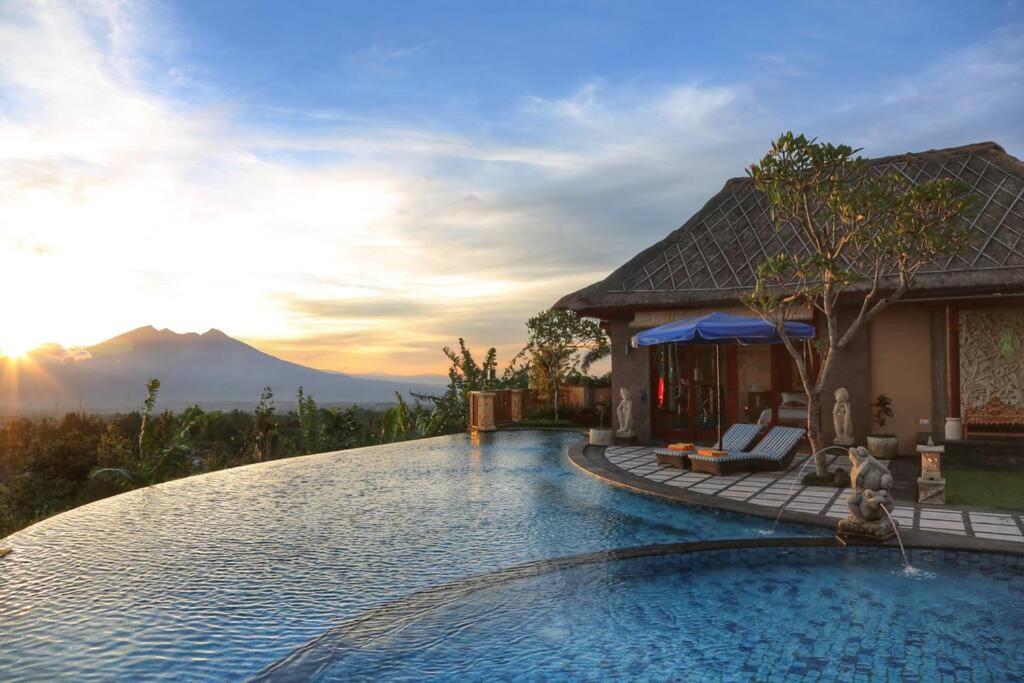 a swimming pool in front of a house with the sunset at PURI BALI STANIA, Cisarua West Java in Cilama