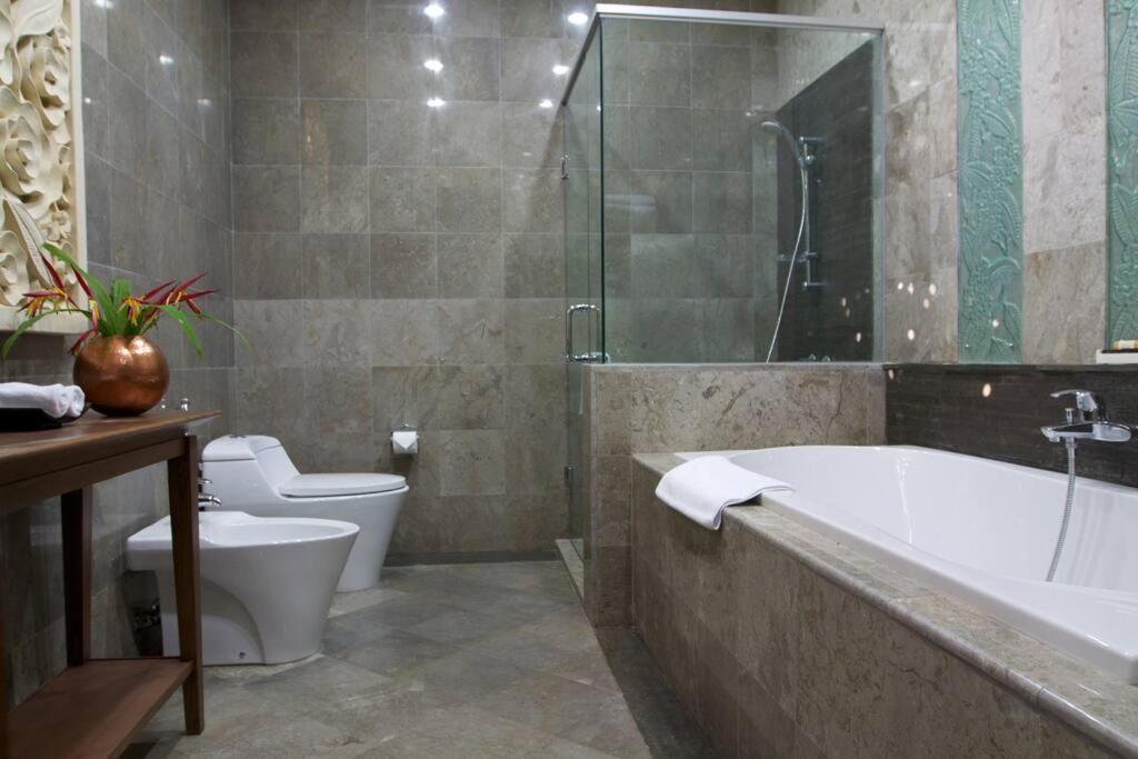 a bathroom with a bath tub and a toilet at PURI BALI STANIA, Cisarua West Java in Cilama
