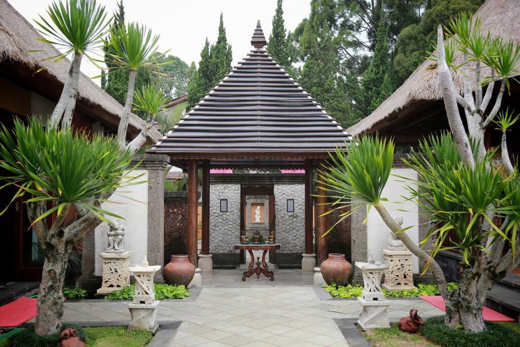 a building with a pavilion in a courtyard with palm trees at PURI BALI STANIA, Cisarua West Java in Cilama