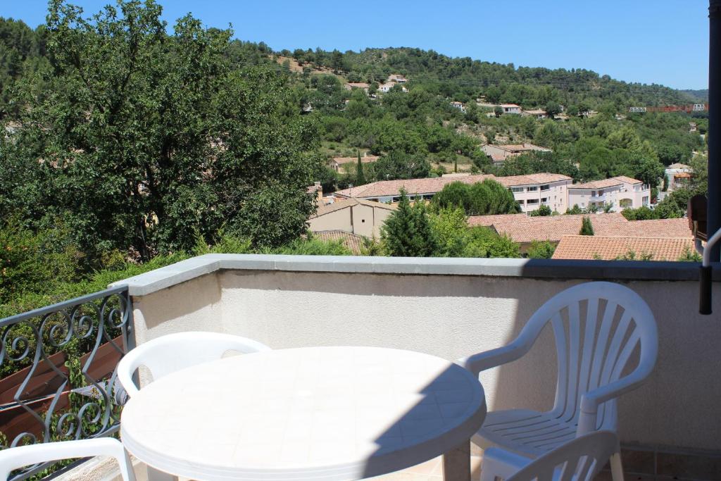 une table blanche et des chaises sur un balcon avec vue dans l'établissement Meublé14 avec terrasse, à Gréoux-les-Bains
