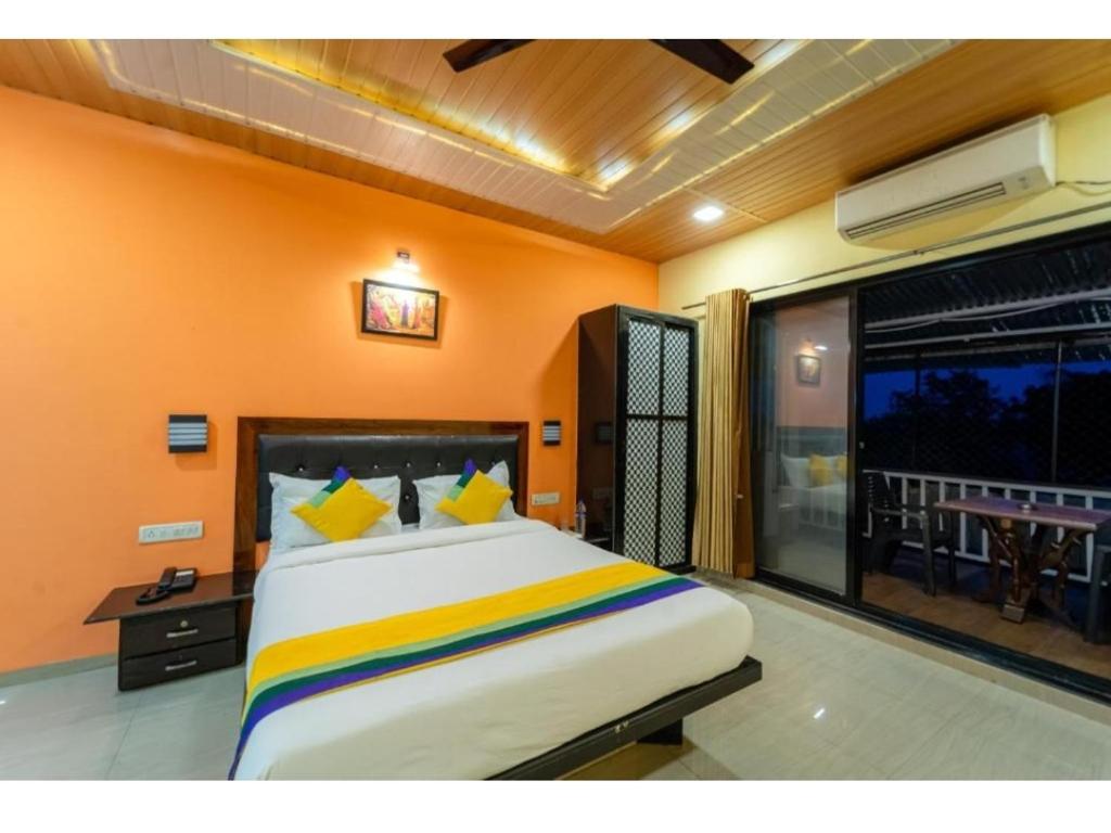 1 dormitorio con 1 cama grande y pared de color naranja en New Sun n S Resort Matheran, en Matheran