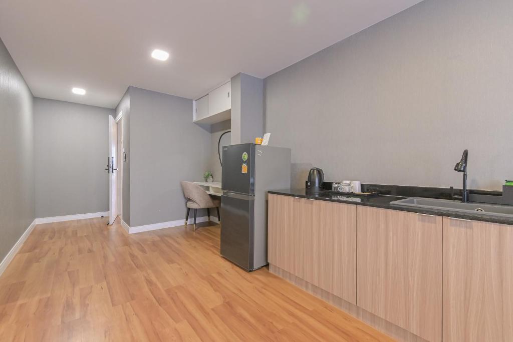 An apartment kitchen with a refrigerator, sink, kettle, cooktop, and compact work nook.