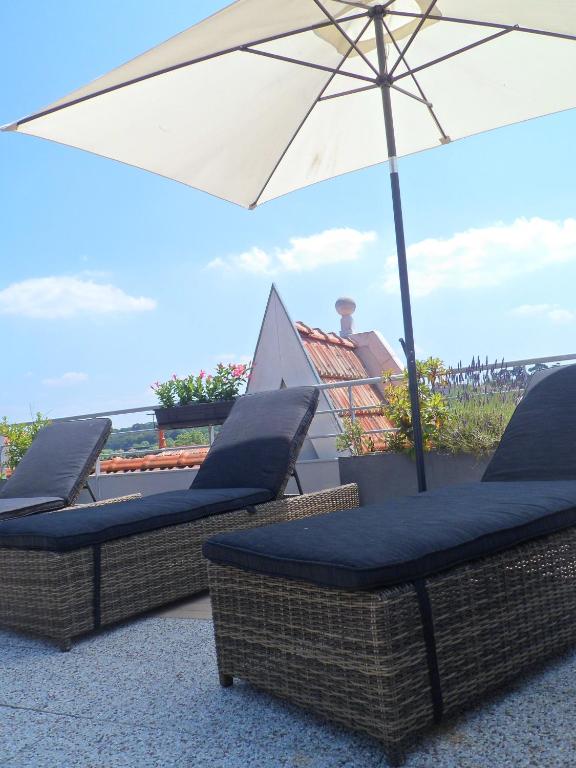 two wicker chairs and an umbrella on a patio at Residhome Arcachon Plazza in Arcachon