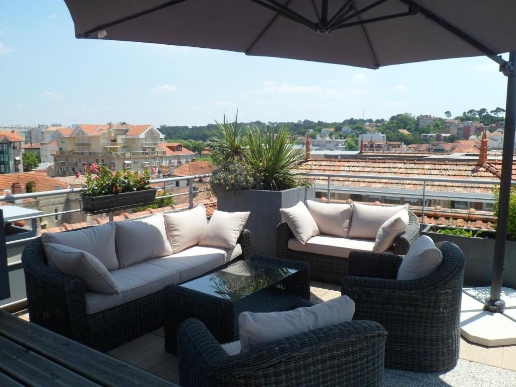 a patio with two couches and an umbrella at Residhome Arcachon Plazza in Arcachon