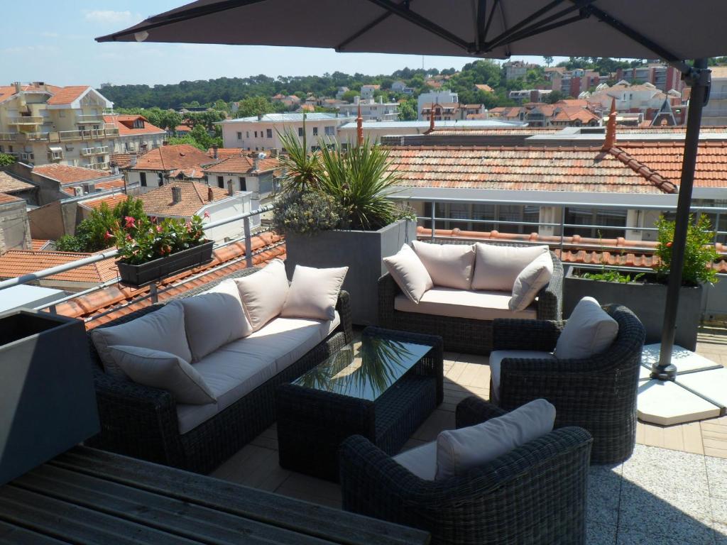a patio with couches and an umbrella on a roof at Residhome Arcachon Plazza in Arcachon
