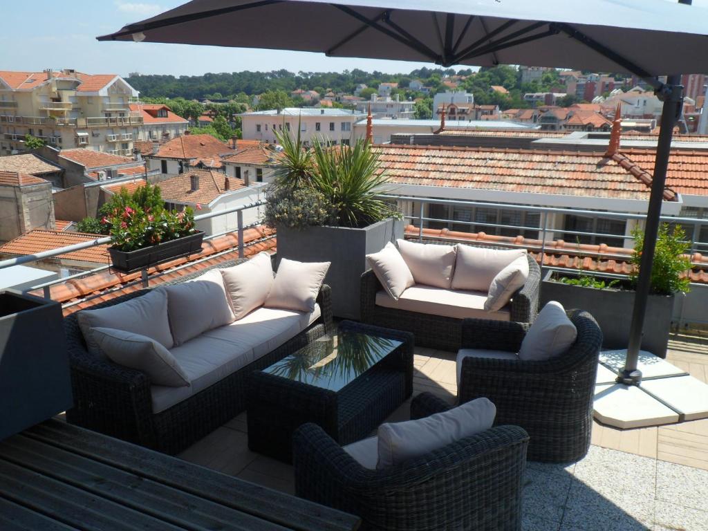 a patio with couches and an umbrella on a roof at Residhome Arcachon Plazza in Arcachon