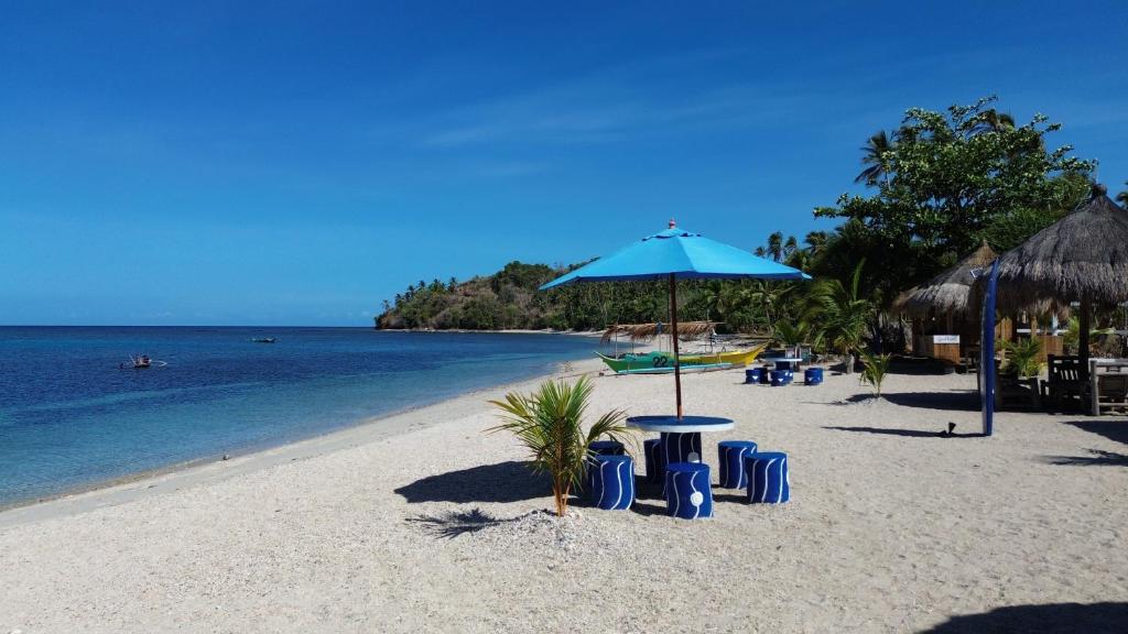 einen Strand mit Sonnenschirm und Stühlen und Wasser in der Unterkunft Dreamshore Ki'wi Beach Resort 