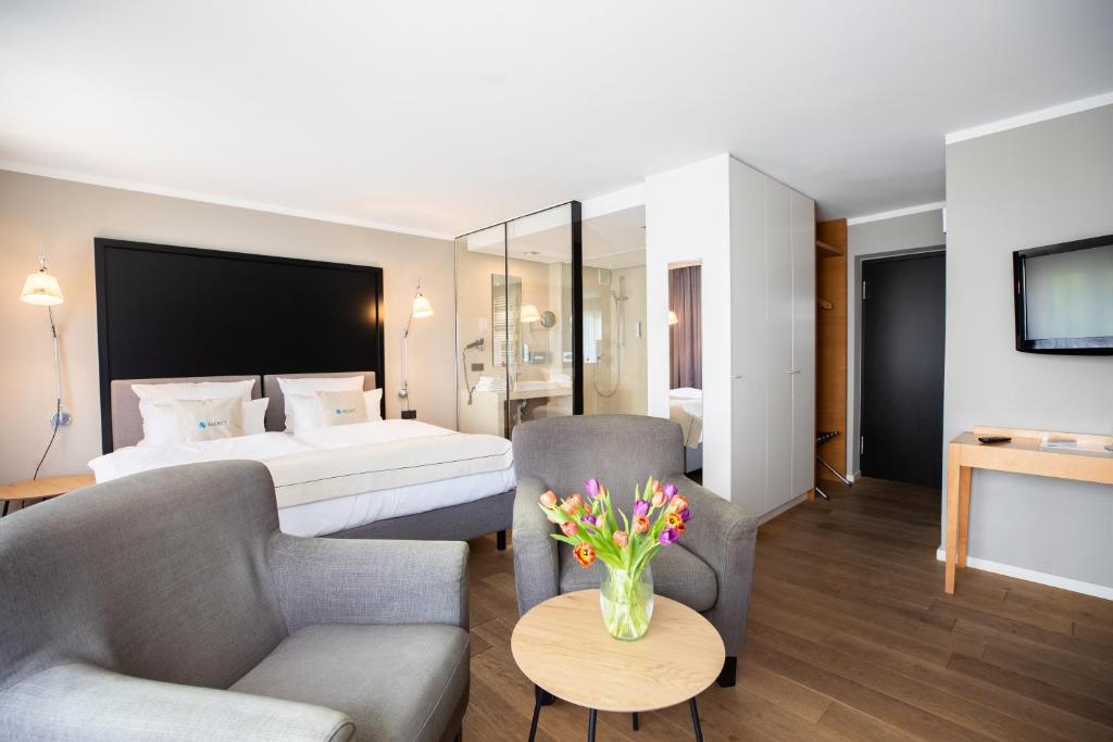 Habitación de hotel con cama y sala de estar. en Select Hotel Friedrichshafen en Friedrichshafen