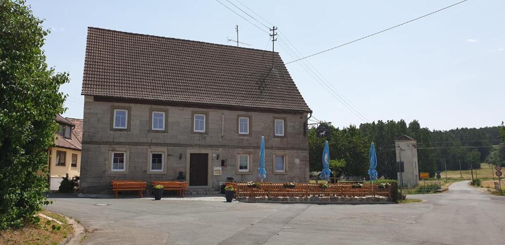 a building with benches and blue flags in front of it at Gasthaus Weißes Ross in Burghaslach