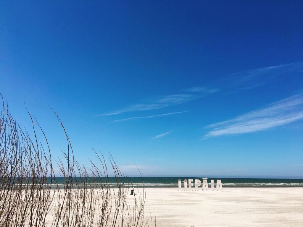 a group of white chairs sitting on a beach at Amber Shore Apartment in Liepāja