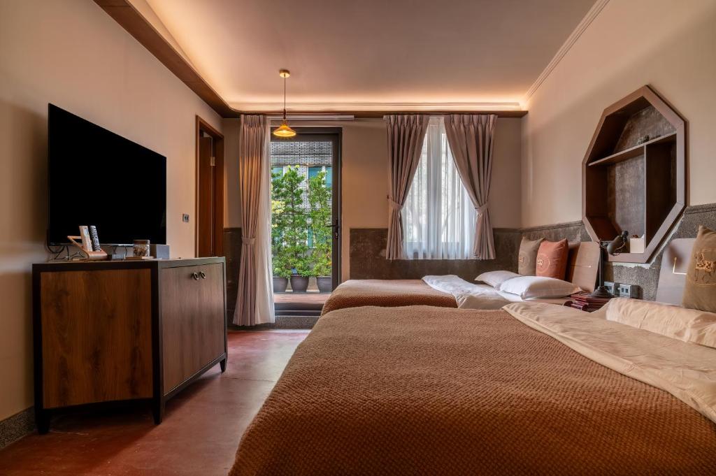 Cette chambre comprend 2 lits et une télévision à écran plat. dans l'établissement 安樓文旅Enzo House, à Keelung