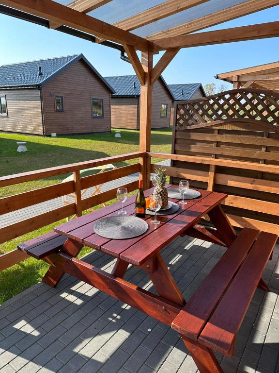 a wooden picnic table with wine glasses on a patio at Zielona Dolina Sarbinowo in Sarbinowo