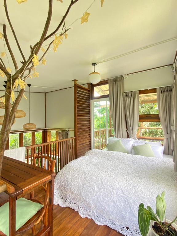 a bedroom with a white bed and a tree at Suksamer Relaxation Homestay 