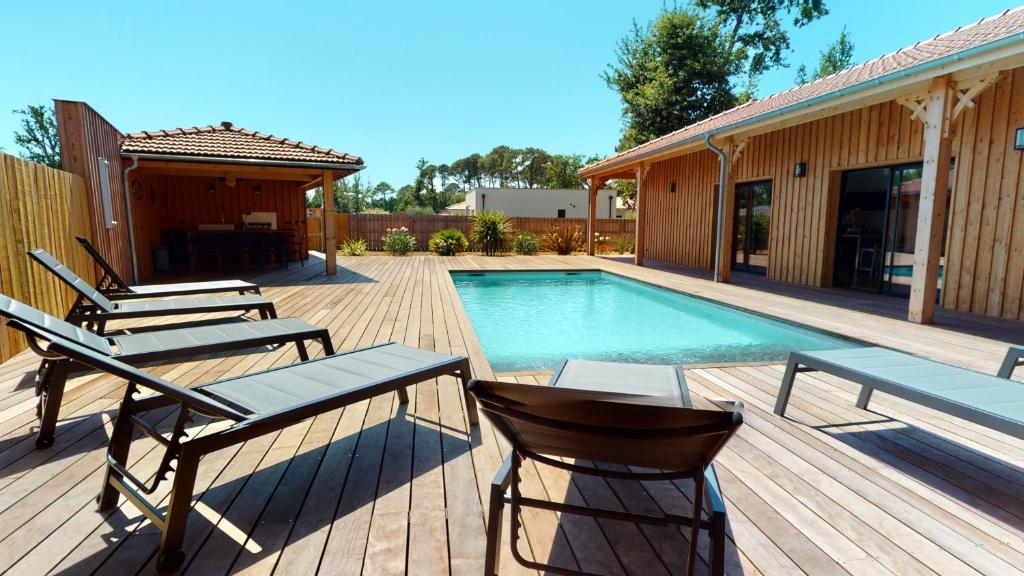 une terrasse avec des chaises et une piscine dans l'établissement Villa avec clim et piscine chauffée Arès Cap Ferret, à Arès