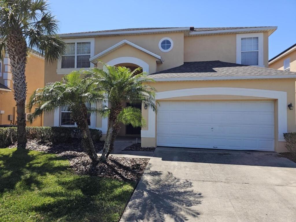 a house with a garage and palm trees in front of it at Spacious 7 BR, 4,5 BR Retreat with Pool 164 condo in Kissimmee