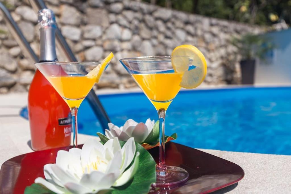 two cocktails sitting on a table next to a pool at Haus Karin in Lovran
