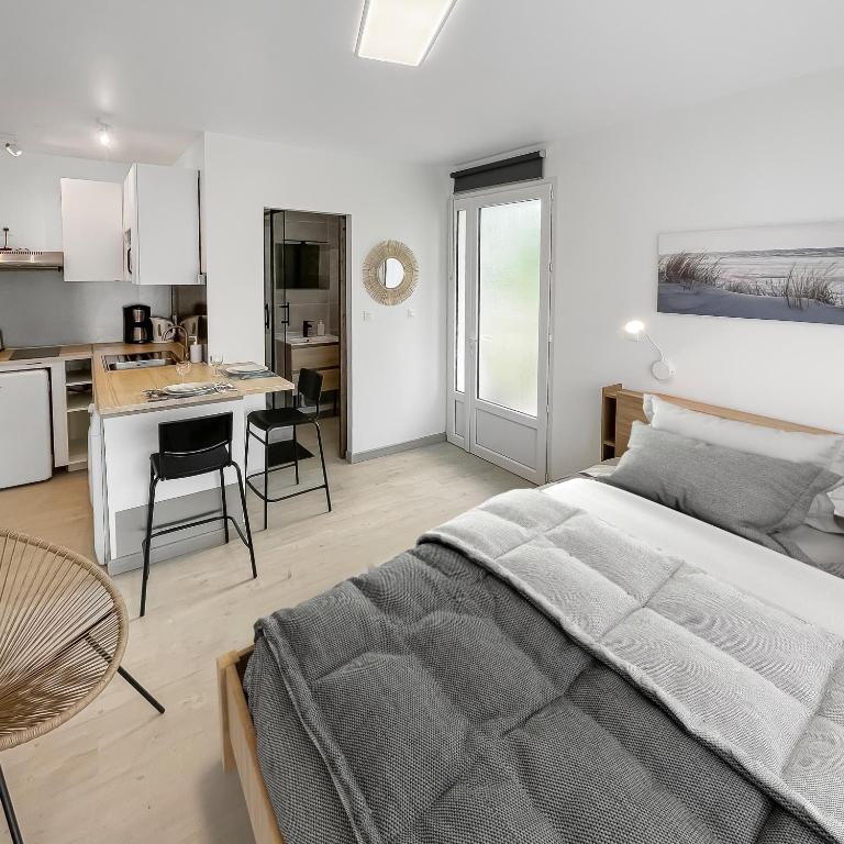 une chambre avec un grand lit et une cuisine dans l'établissement Studio entre Bordeaux et l'Atlantique avec Jacuzzi, à Saint-Médard-en-Jalles