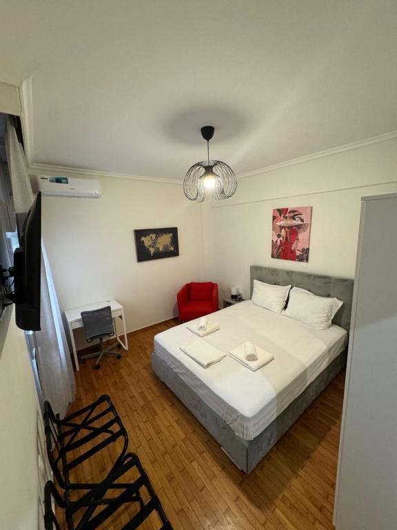 um quarto com uma cama branca e uma cadeira vermelha em The Nest em Tessalônica
