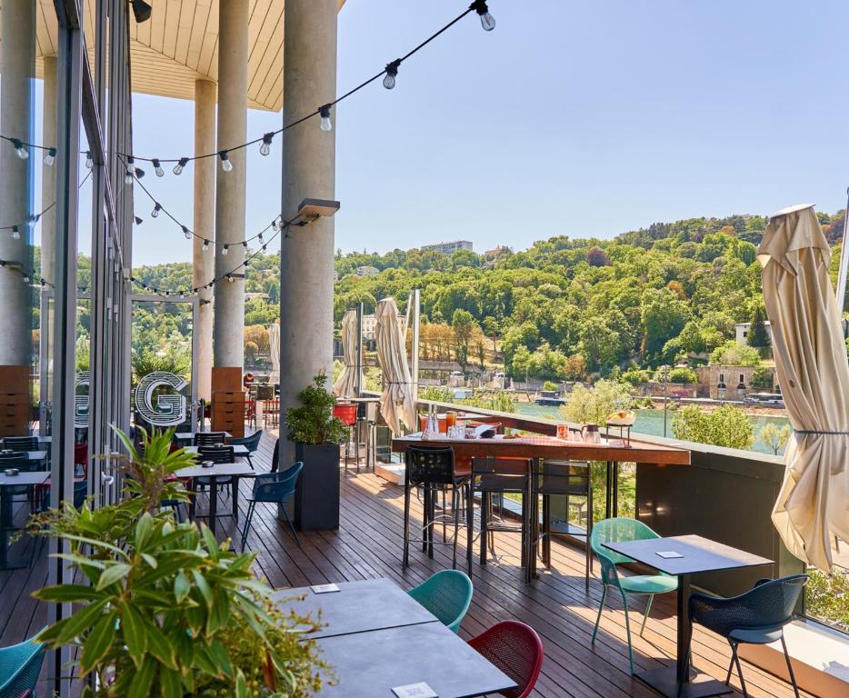 un restaurante con mesas y sillas y vistas al río en Novotel Lyon Confluence, en Lyon