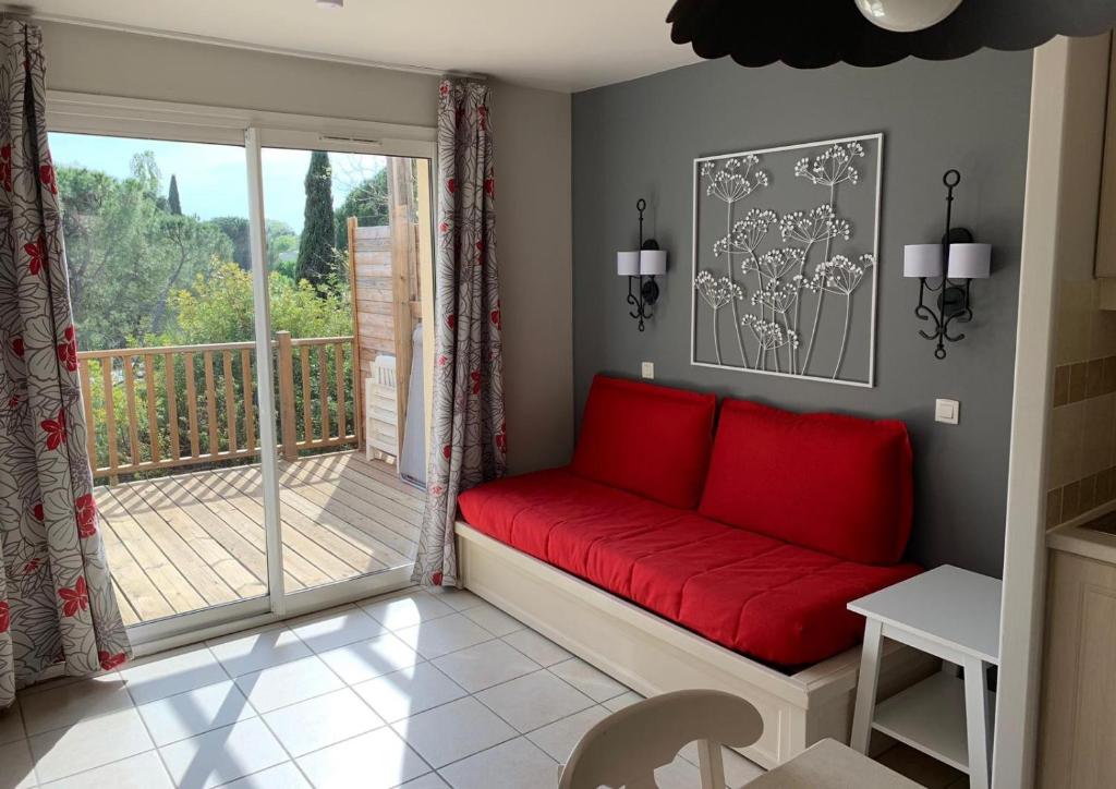 un salon avec un canapé rouge et un balcon dans l'établissement Maison duplex - Domaine P&V Le Rouret - Proche Vallon Pont d'Arc, à Grospierres