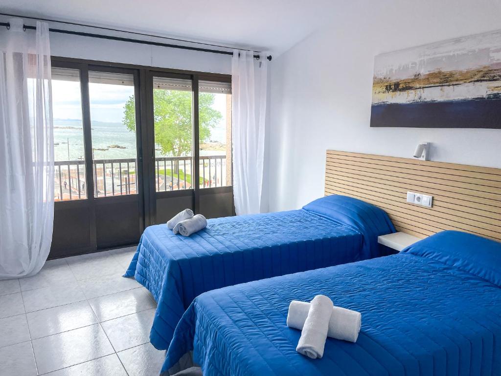 um quarto de hotel com duas camas e uma varanda em Hostal Tamanaco Illa de Arousa 3000 em Ilha de Arousa
