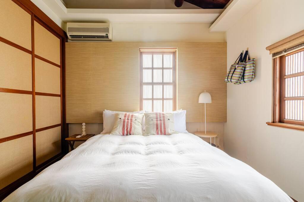 a large white bed in a room with a window at 臺窩灣Tayouan Villa2024全新房間設備包棟不分租,4房6衛4床2廳1廚房,安平古堡老街走路1分鐘,花園夜市15分 in Anping