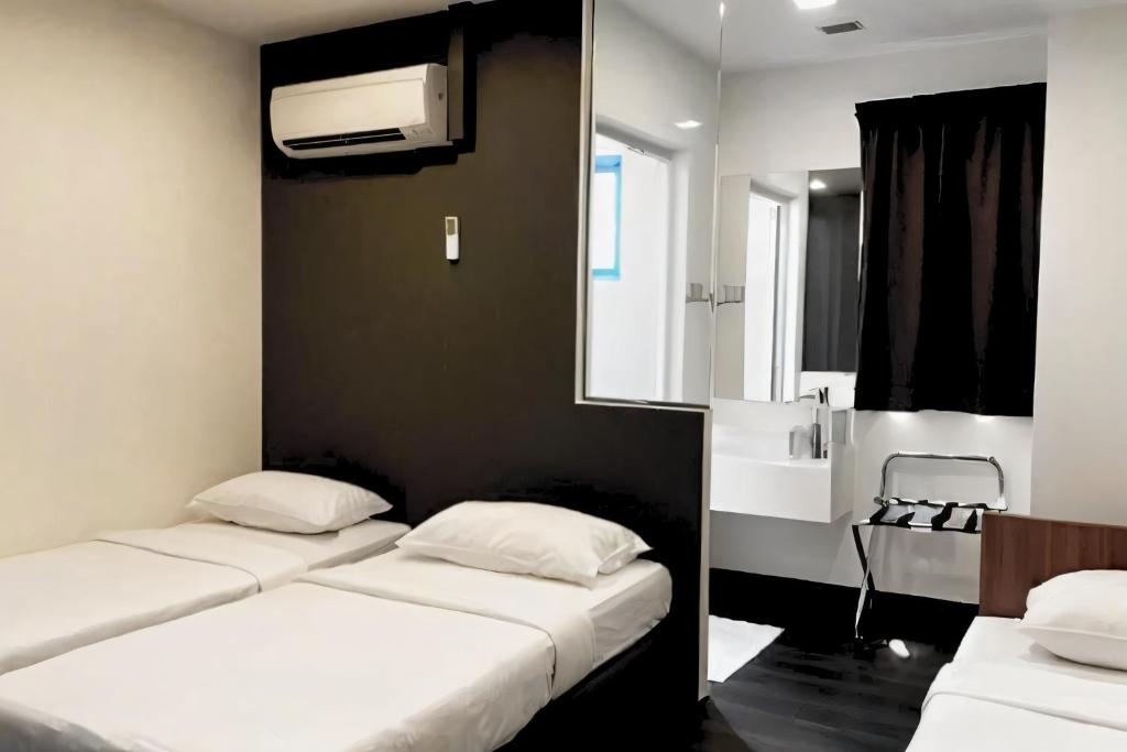 two beds in a small room with a window at L Hotel at 51 Desker in Singapore