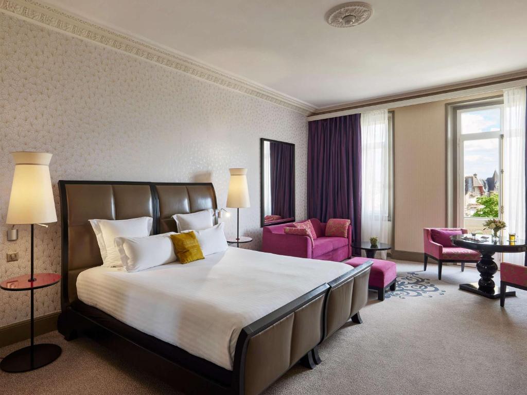 a hotel room with a bed and two chairs at Le Grand Hotel de Cabourg - MGallery Collection in Cabourg