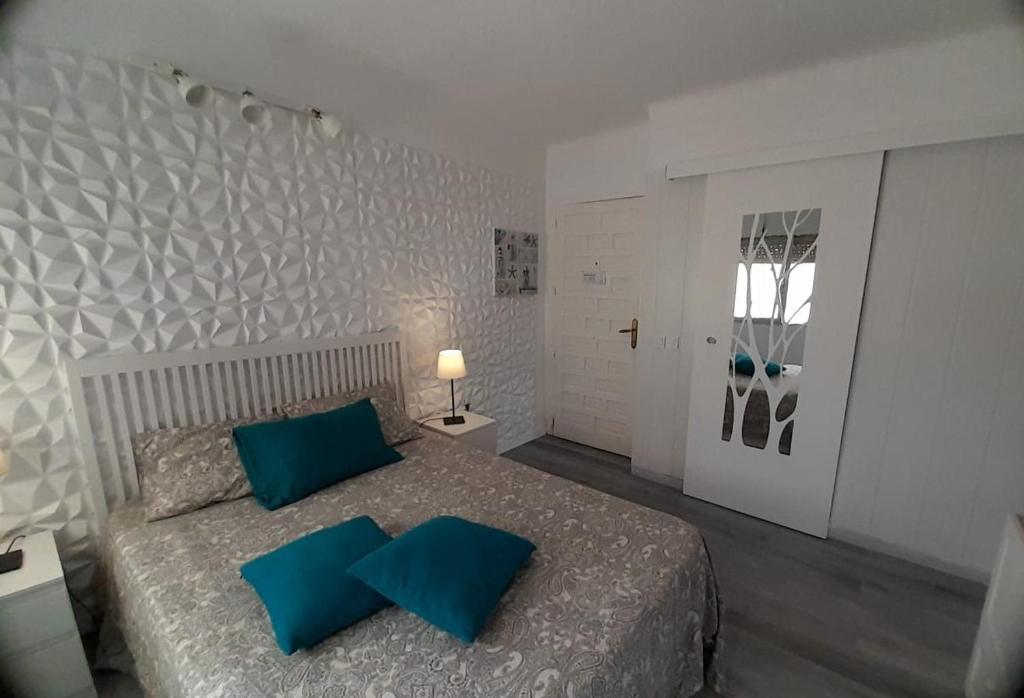ein Schlafzimmer mit einem großen Bett mit blauen Kissen in der Unterkunft Apartamento una habitación supercéntrico in Torremolinos