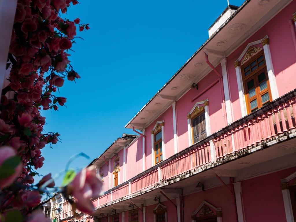 a pink building with windows and a balcony at Novotel Phuket City Phokeethra in Phuket Town