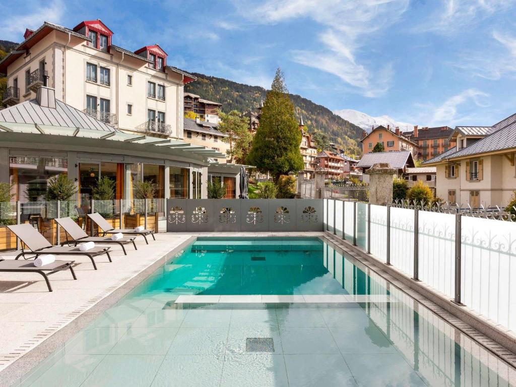 una piscina con sedie e un edificio di Le Saint Gervais Hotel & Spa Handwritten Collection a Saint-Gervais-les-Bains