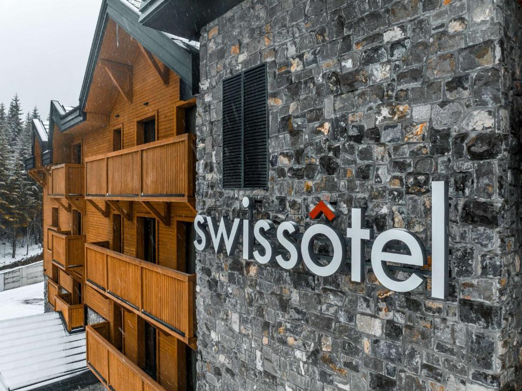 un edificio de piedra con un letrero de ayssote en el costado. en Swissôtel Resort Kolasin en Kolašin