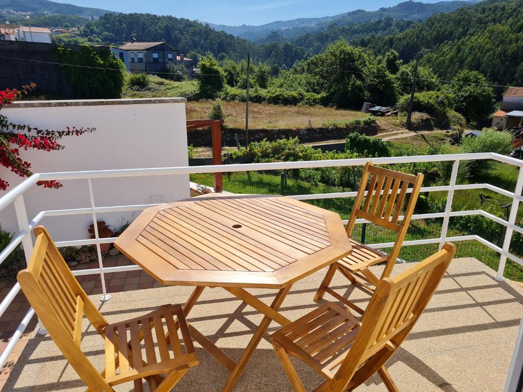 Coliving The VALLEY Portugal private bedrooms with a single or a double bed, a shared bedroom with a bed and futons, shared bathrooms and a coworking space open 24-7 في فالي دي كامبرا: طاولة خشبية وكرسيين على شرفة
