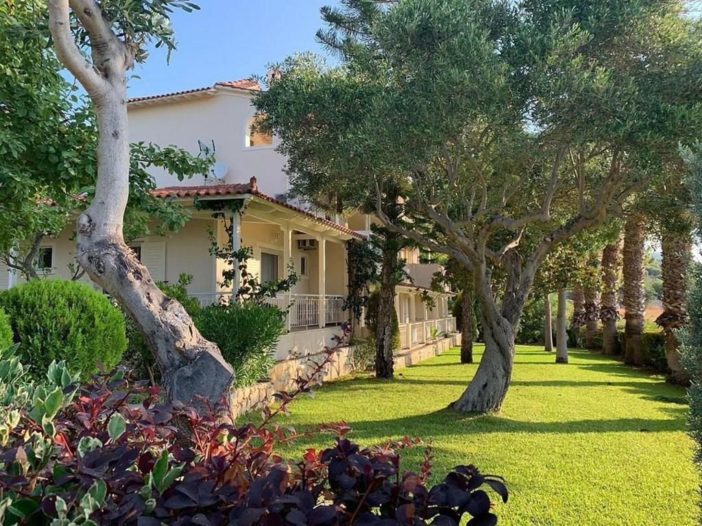 a house with trees in front of a yard at Villa Kastri Apartments in Vasiliki