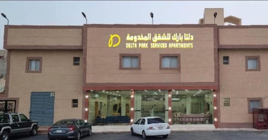 un grand bâtiment avec des voitures garées devant lui dans l'établissement دلتا بارك للشقق المخدومة DELTA PARK SERVICED APARTMENTs, à Riyad