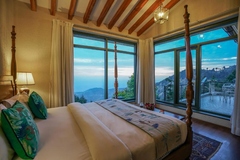 a bedroom with a bed in front of a large window at Larisa Resort, Mussoorie in Mussoorie