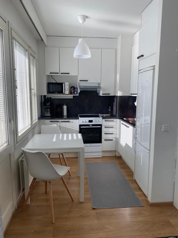 a white kitchen with a table and a chair at Tilava yksiö Niinivaaralla in Joensuu