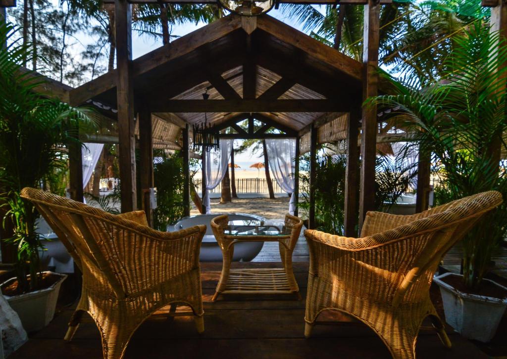 a patio with wicker chairs and a table in a pavilion at Larisa Beach Resort in Morjim