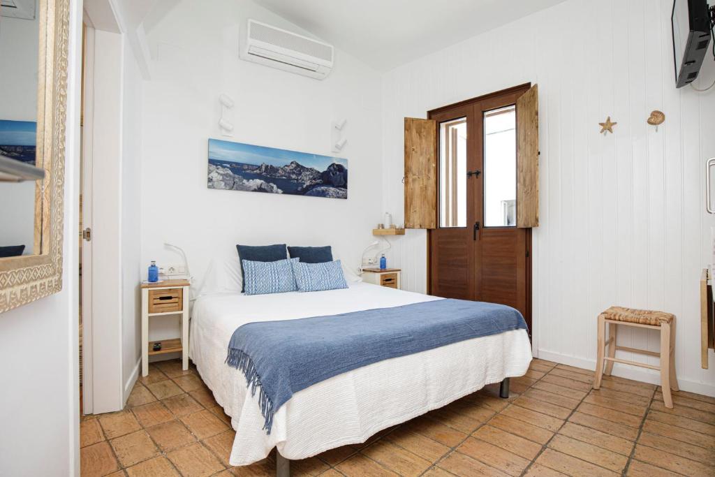 a white bedroom with a bed and a window at L'Hostalet de Cadaques in Cadaqués