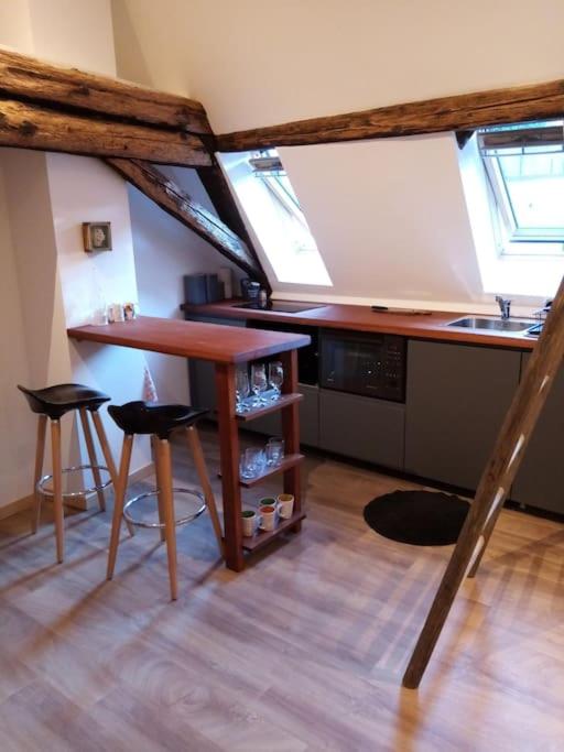 une cuisine avec une table en bois et deux tabourets dans l'établissement Studio cosy dans maison alsacienne, à Gueberschwihr