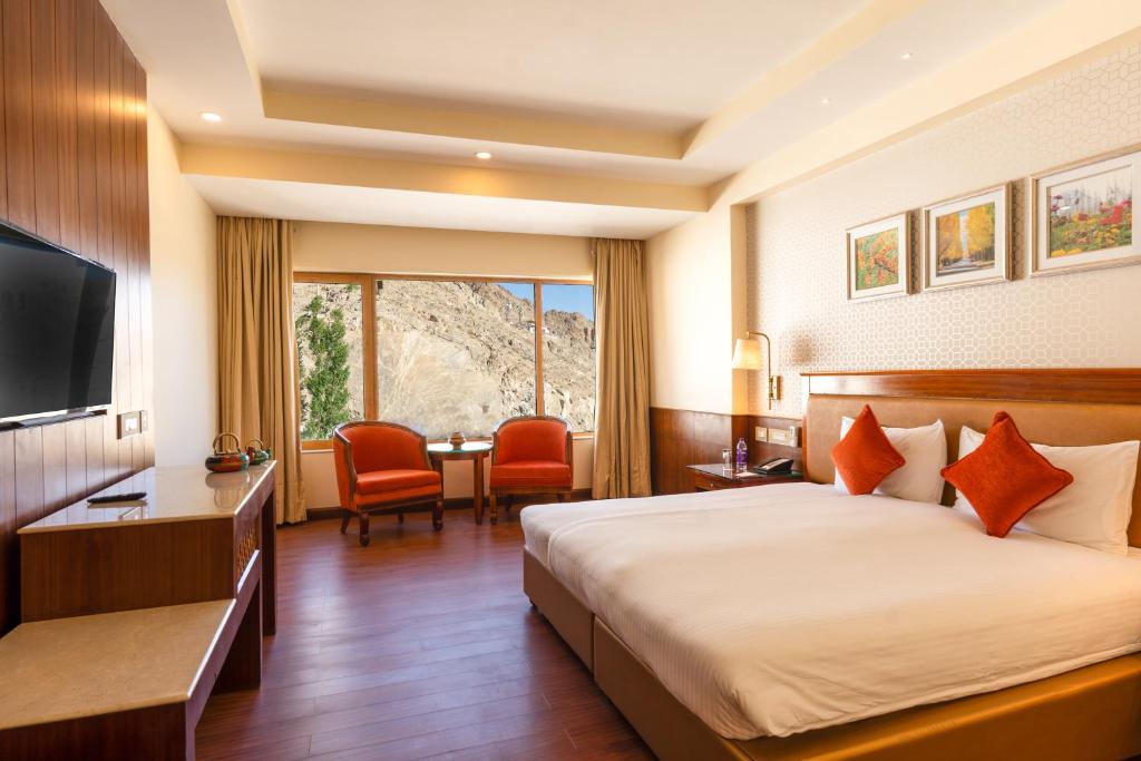 Habitación de hotel con cama, escritorio y TV. en Hotel Dragon Leh, en Leh