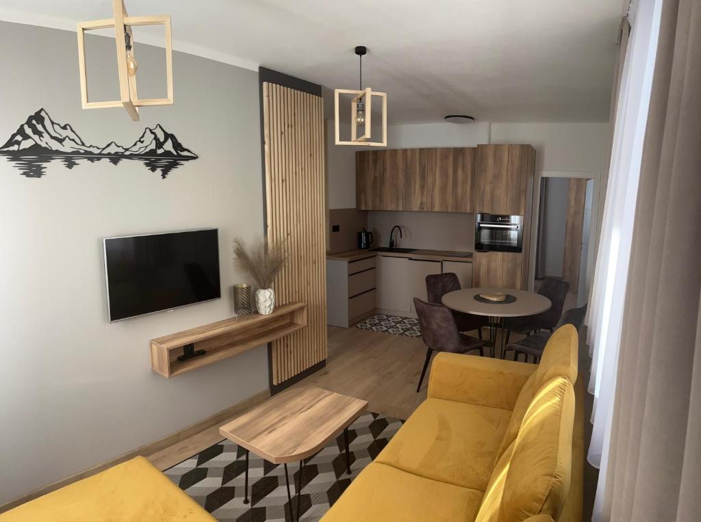 a living room with a yellow couch and a kitchen at Apartman Valnela in Veľká Lomnica
