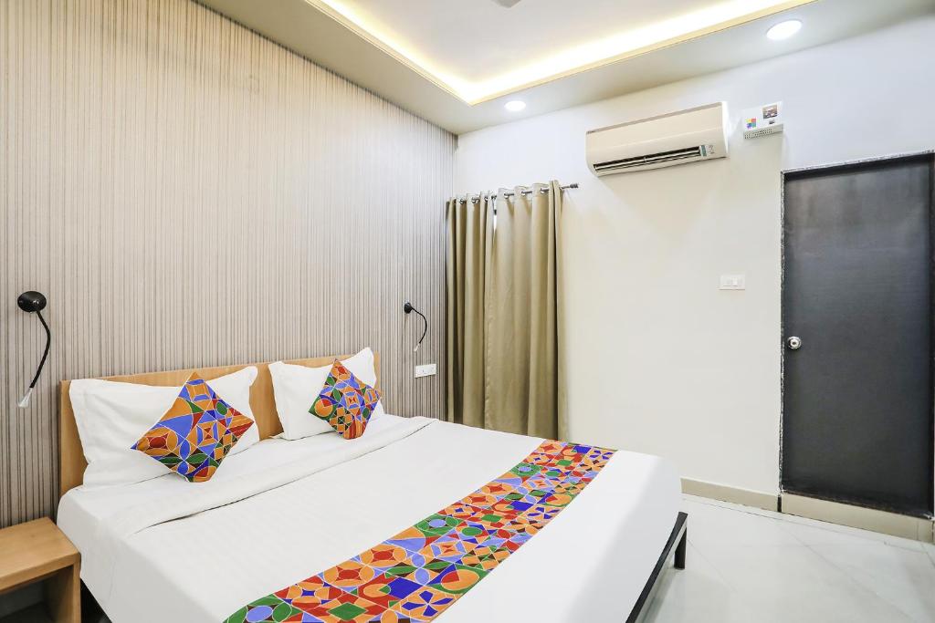 1 dormitorio con 1 cama blanca grande con almohadas coloridas en FabHotel Convivial Sky, en Raipur